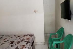 Habitación con cama y silla verde en SPOT ON 93005 Berkah Kedawung Syariah en Cirebon