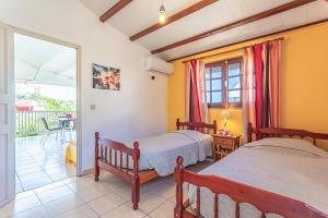 a bedroom with two beds and a balcony at Résidence Pommes Cannelles in Bouillante