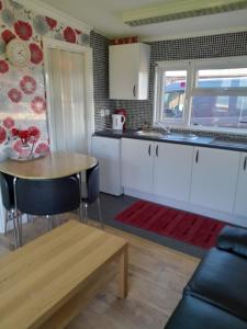cocina con armarios blancos y mesa de madera en B8 lovely chalet en Mablethorpe