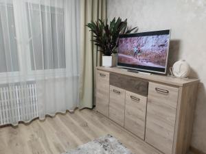 a television sitting on top of a wooden dresser at Patogus poilsis prie ežero/Comfortable rest in Visaginas