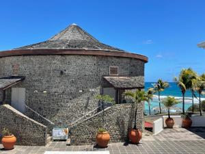 a brick building with palm trees and the ocean at Studio Climatisé avec Réservoir d'eau in Saint-François