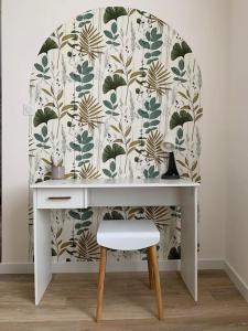 a white desk with a chair in front of a wallpaper at Maison individuelle in Vincey