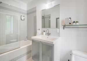 W łazience znajduje się umywalka, wanna i lustro. w obiekcie Loft The White Pearl Plateau-Mont-Royal 3 Beds w Montrealu