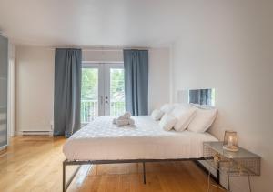 a bedroom with a large bed with a teddy bear on it at Loft The White Pearl Plateau-Mont-Royal 3 Beds in Montréal