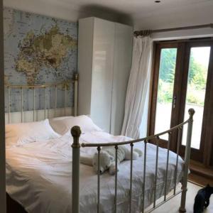 a white cat laying on a bed in a bedroom at Prestwick Oak - 2 Luxury Ensuite Doubles - Sleeps 4-6 - Rural Quirky Contemporary in Chiddingfold