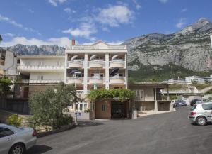 un bâtiment avec des voitures garées dans un parking avec des montagnes dans l'établissement Apartments Kovač, à Makarska