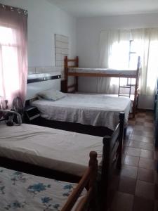 a room with two beds and two bunk beds at Pousada Bom Jesus in Ponta Grossa