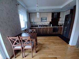 グニェズノにあるPrzytulny Apartament w Gnieźnieのキッチン(木製のテーブル、椅子付)