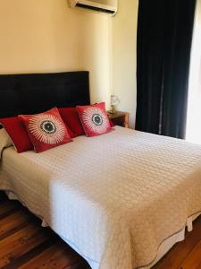 1 dormitorio con cama blanca y almohadas rojas en Departamento a 1 cuadra de calle Aristides en Mendoza