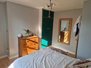 een slaapkamer met een bed, een dressoir en een spiegel bij Stylish-Brockley-Entire Place in Londen