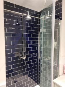 een badkamer met een douche met blauwe tegels en een glazen deur bij Stylish-Brockley-Entire Place in Londen