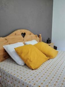 Una cama con almohadas amarillas y blancas. en LE MAZOT-SPA HIVER ET ETE-Piscine-Proche lac-Charme-Détente, en Lathuile