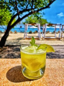 a drink sitting on a table on the beach at Hotel Rosario de Mar by Tequendama in Isla Grande