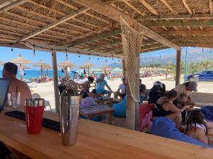 un grupo de personas sentadas en un bar en la playa en Blue Paradise Hotel, en Orikum