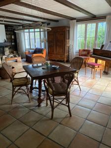 a living room with a table and chairs and a piano at La maison du petit bonheur in Moutier