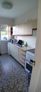 uma cozinha com armários brancos, um lavatório e um fogão em ATLANTIC VIEW PORTNOO em Clogher