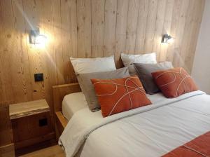 ein Schlafzimmer mit einem Bett mit zwei orangefarbenen Kissen in der Unterkunft *Spacieux T3 Campagne proche lac* in Magland