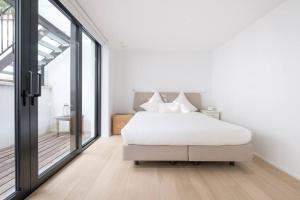 a bedroom with a white bed and a large window at Spacious 1-bedroom duplex in Uccle! in Brussels
