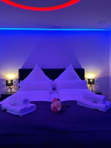 a bed with white sheets and pillows in a blue room at Modern Apartments Neuburg 3 - TOP NEU - 2 Zimmer, Komfort, Balkon, Wi-Fi, Smart TV, Badewanne, Küche in Neuburg an der Donau