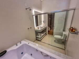 a white bathroom with a tub and a toilet at Mosteiro Hotel de Charme próximo ao Vale dos Vinhedos in Garibaldi