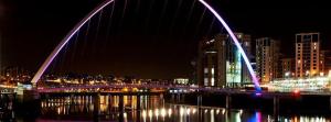 un puente iluminado sobre un río por la noche en Millennium Apartments en Newcastle