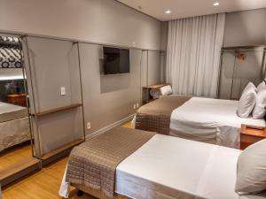 um quarto de hotel com duas camas e uma televisão em Mosteiro Hotel de Charme próximo ao Vale dos Vinhedos em Garibaldi
