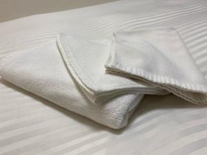 a pile of white towels sitting on top of a bed at A&Bee HOTEL - Vacation STAY 35415v in Oita