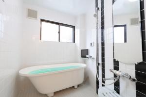een bad in een witte badkamer met een raam bij NAOMI - Vacation STAY 15281 in Osaka