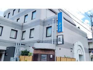 un edificio con una señal azul delante de él en Business Inn Suwabe - Vacation STAY 46132v en Kurayoshi