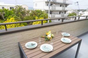 uma mesa de madeira com pratos e copos numa varanda em White Terrace D - Vacation STAY 44940v em Nakadomari