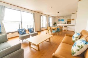 uma sala de estar com um sofá e uma mesa com cadeiras em White Terrace D - Vacation STAY 44940v em Nakadomari