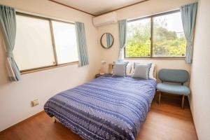um quarto com uma cama, uma cadeira e janelas em White Terrace D - Vacation STAY 44940v em Nakadomari