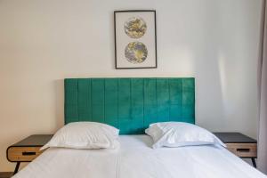 a bed with a green headboard and two pillows at Nice apartment 4P- Levallois Anatole France in Levallois-Perret