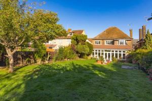a large house with a yard with green grass at Rose Garden House in Luton