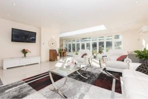 a living room with white furniture and a flat screen tv at Rose Garden House in Luton