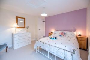 1 dormitorio con 1 cama blanca grande y espejo en No. 10, The Cottage, en Framlingham