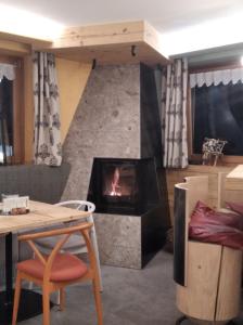 a living room with a fireplace and a table and chair at Rifugio La Montanara in Molveno
