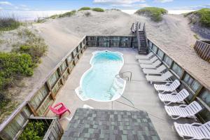 an overhead view of a swimming pool with lounge chairs and a beach at 5727 - Whalebone Station by Resort Realty in Nags Head