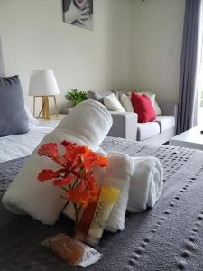 a bed with towels and a vase of flowers on it at Convenient Studio Apt Near Airport, Beaches & Food in Cupecoy