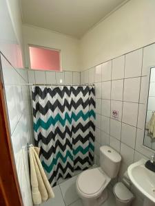 a bathroom with a toilet and a shower curtain at Hostal Boutique F in El Quisco