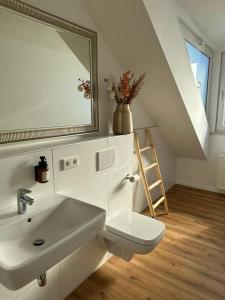 La salle de bains blanche est pourvue d'un lavabo et d'un miroir. dans l'établissement Mango Living - Stadtoase in Mönchengladbach, 95 qm, spacious, 3 Schlafzimmer, Nähe Hauptbahnhof, à Mönchengladbach