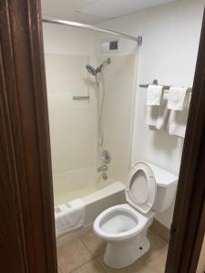 ein Bad mit einem WC und einer Dusche mit Handtüchern in der Unterkunft Bedford Inn in Elk City