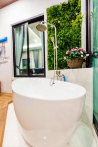 baño con bañera blanca y ventana en White Cloud & Brown Sand Luxury Pool Villa Cha-Am en Cha Am