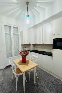 a kitchen with white cabinets and a table with flowers on it at CHEZ TAMARA in Nice