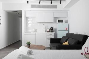 a living room with a black couch and a kitchen at דירת סטודיו מעוצבת 50 מטר מהים - By Edomlux in Eilat