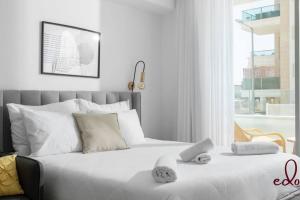 a white bed with two towels on top of it at דירת סטודיו מעוצבת 50 מטר מהים - By Edomlux in Eilat