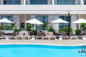 a group of chairs and umbrellas next to a pool at דירת סטודיו מעוצבת 50 מטר מהים - By Edomlux in Eilat