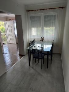 uma sala de jantar com uma mesa de vidro e cadeiras em Jani vendégház em Balatonfüred