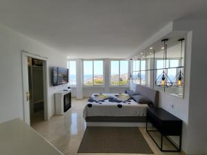 a white bedroom with a bed and windows at Marbella edificio Puerto Azul in Marbella