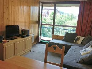 ein Wohnzimmer mit Sofa und Fernseher in der Unterkunft Appartement cosy, centre station, balcon, wifi gratuit - FR-1-346-435 in Arc 1800